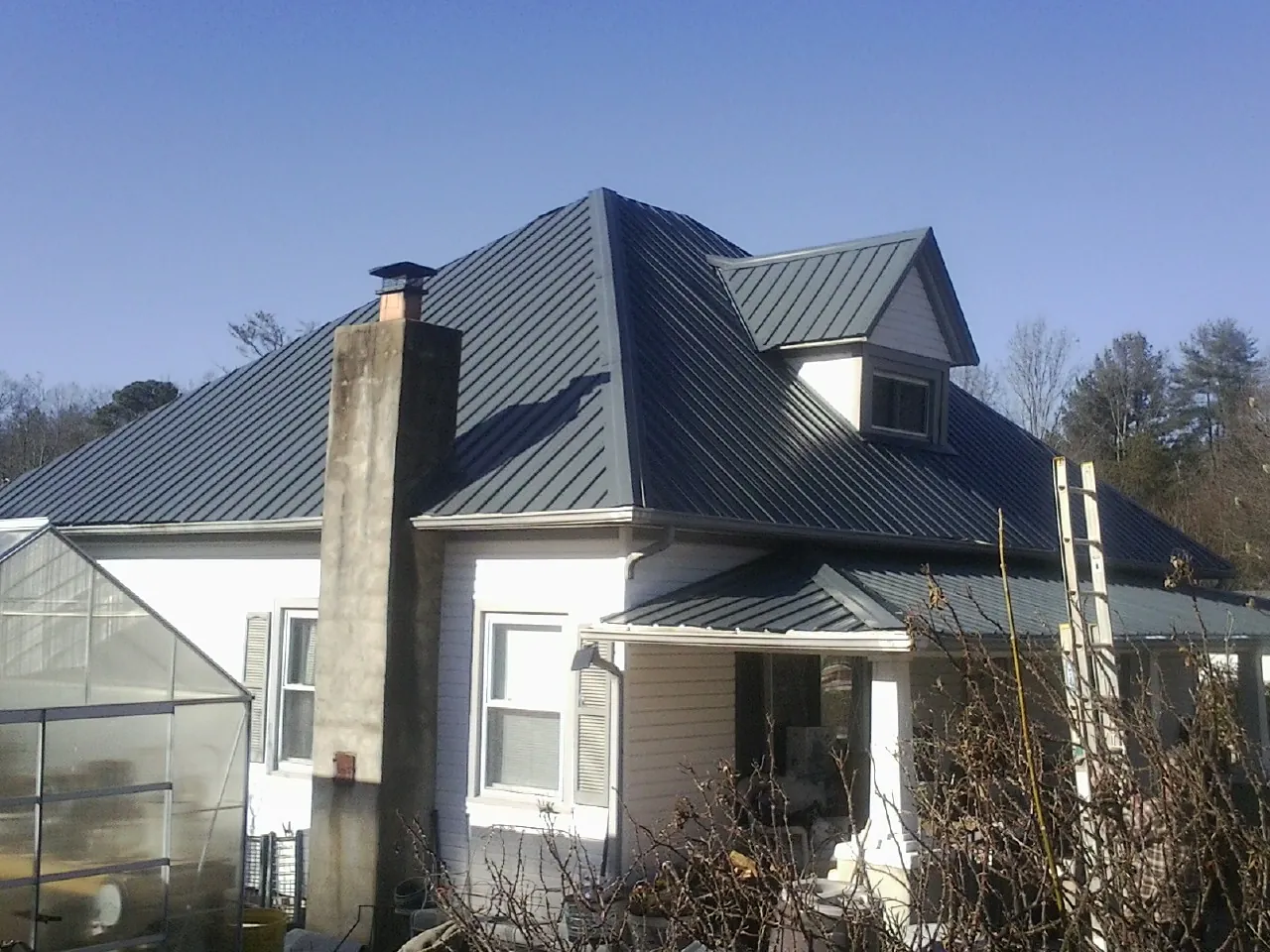 Dark blue standing seam metal roof on a white farmhouse with dormer — Slate & Tile Roof Repair by Roofing Brothers in Beechmont
