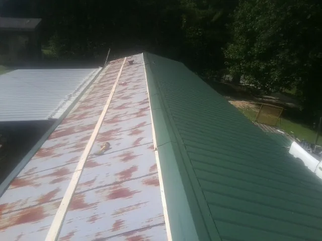 Old rusted panels beside newly installed green metal roofing — Wind Damage Roof Repair by Roofing Brothers in Beechmont