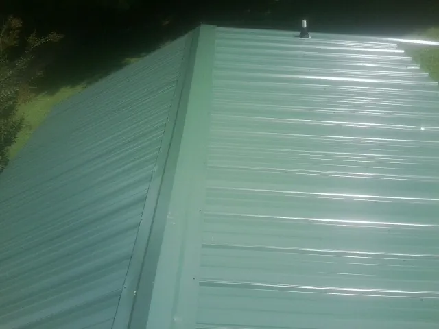 New green metal panels meeting at the ridge of a roof — Flat Roof Repair work by our crew in Beechmont