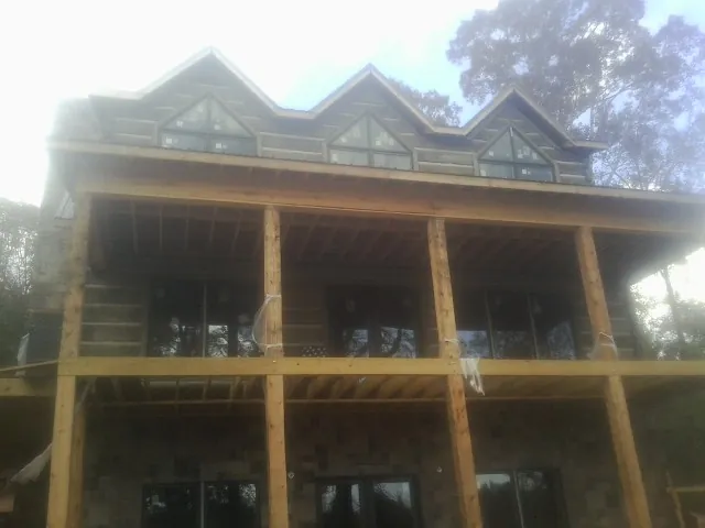 Dormers and porch framing on a large log home under construction — Roof Coating work by our crew in Beechmont