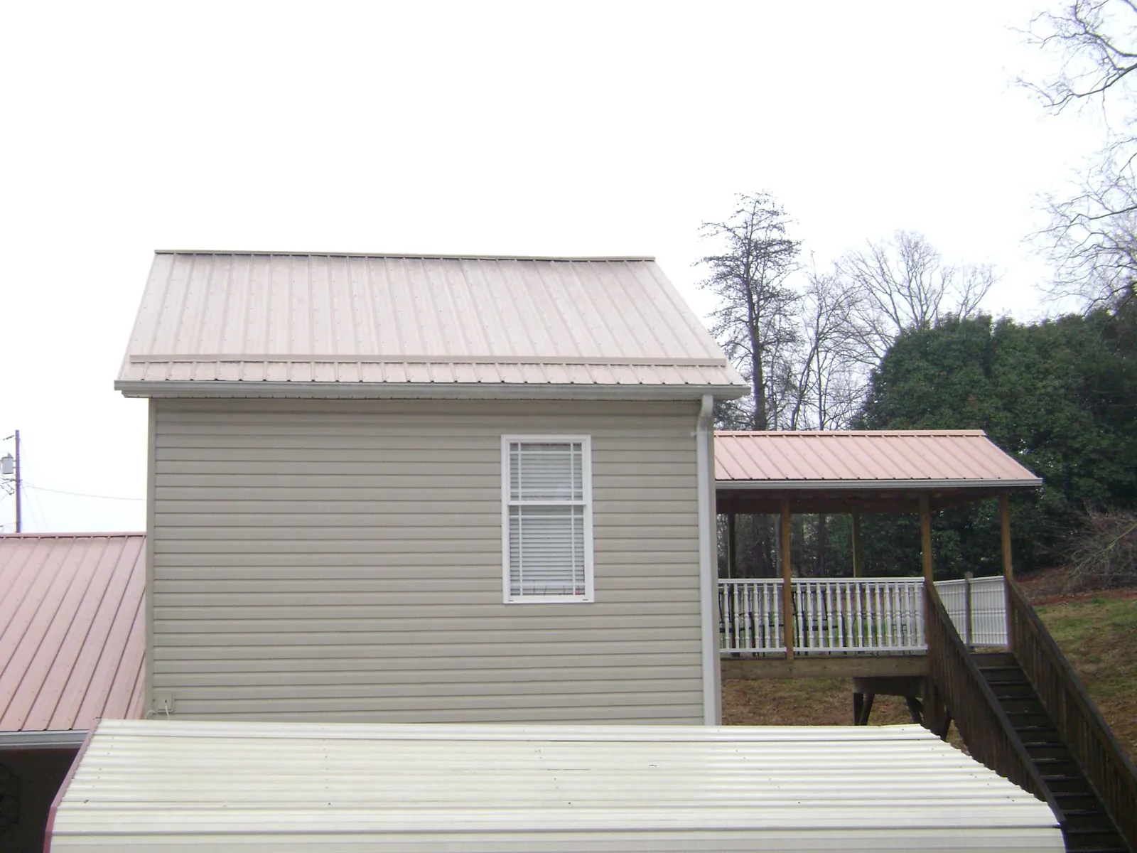 Tan metal roofs on a two story addition and attached porch, from a Roof Replacement job in Beechmont