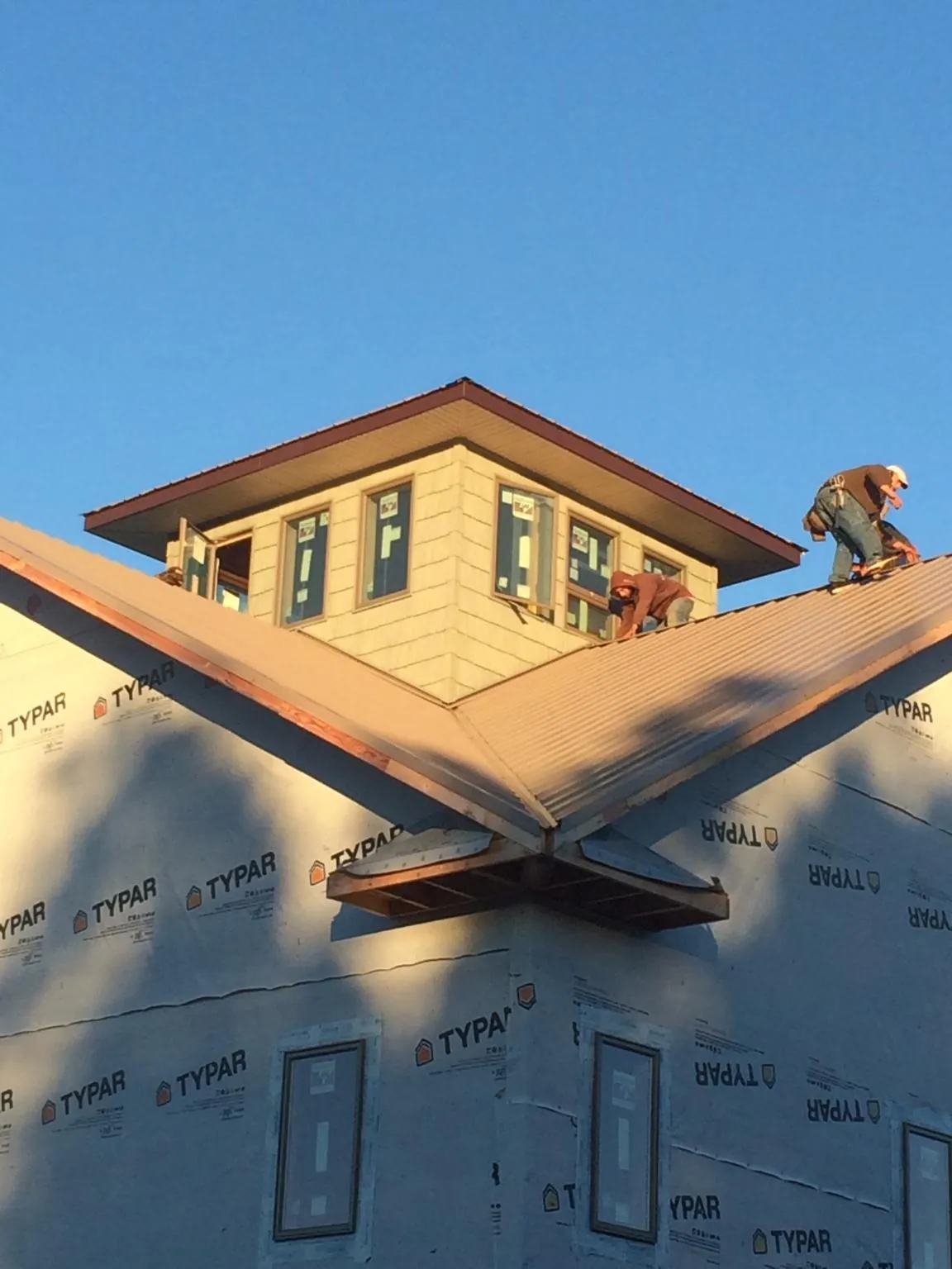 Roofers working around a rooftop cupola on a new metal roof at sunset — Roof Waterproofing in Beechmont by Roofing Brothers